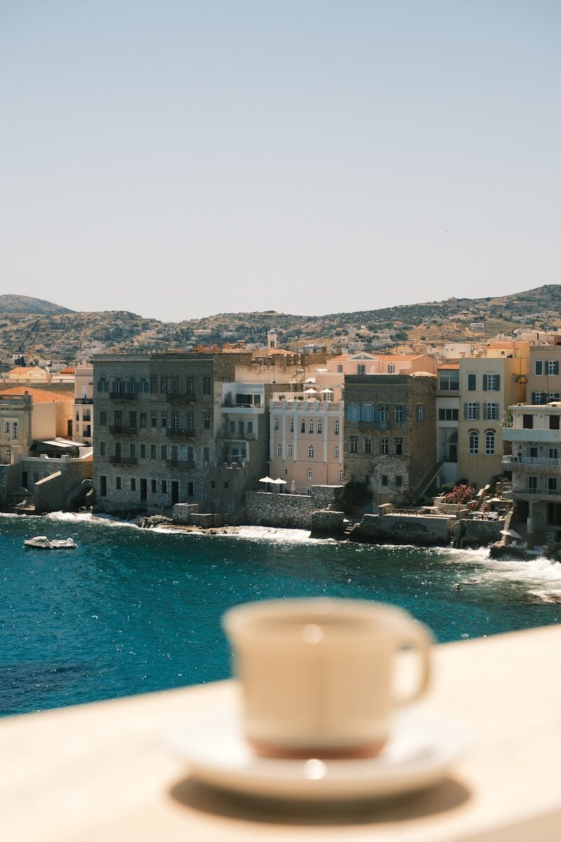 Coffee cup overlooking a coastal town and blue sea.